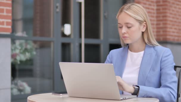 Jonge zakenvrouw in shock tijdens het werken op een laptop buiten — Stockvideo