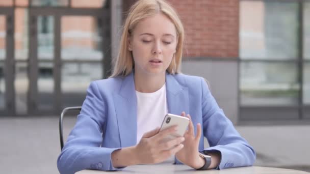 Młody businesswoman korzystanie Smartphone siedzący na wolnym powietrzu — Wideo stockowe