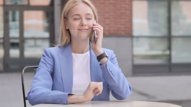Giovane donna d'affari che parla al telefono seduta all'aperto — Video Stock