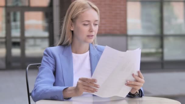 Joven empresaria leyendo documentos mientras está sentada al aire libre — Vídeos de Stock