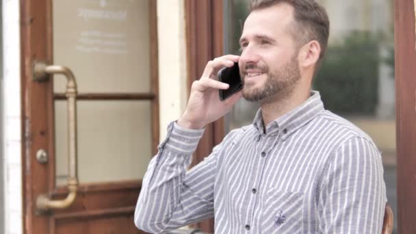 Giovane uomo parlando al telefono mentre seduto all'aperto — Video Stock