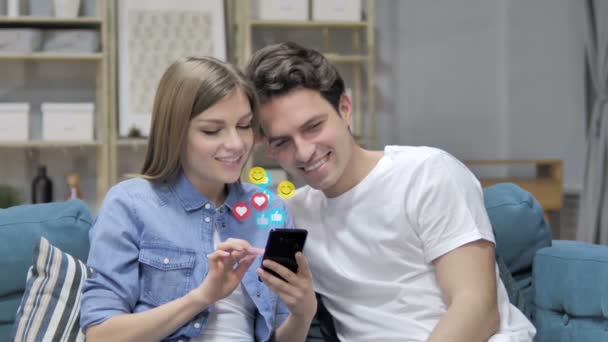 Sonriendo joven pareja usando Smartphone, Volando emoticonos, emoticonos y gustos — Vídeo de stock