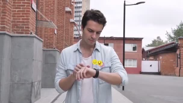 Vandrende ung mann som bruker Smartwatch, Flying Smileys, Emojis og Likes – stockvideo