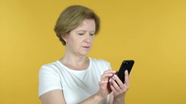 Sarı arka planda yalıtılmış eski kadın tarama Smartphone