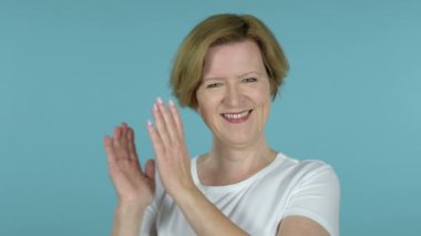 Mavi arka planda yalıtılmış alkışlamak yaşlı kadın tebrik