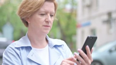 Akıllı telefon kullanırken başarı için açık eski kadın heyecanlı