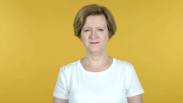 Gammal kvinna viftande hand att välkomna isolerade på gul bakgrund — Stockvideo