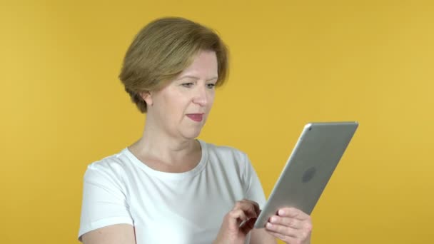 老妇人通过平板电脑在黄色背景上隔离的视频聊天 — 图库视频影像