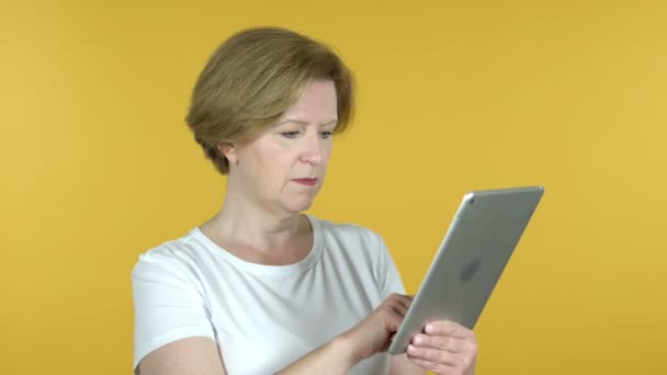 Mujer vieja reaccionando a la pérdida en la tableta aislada sobre fondo amarillo — Vídeos de Stock