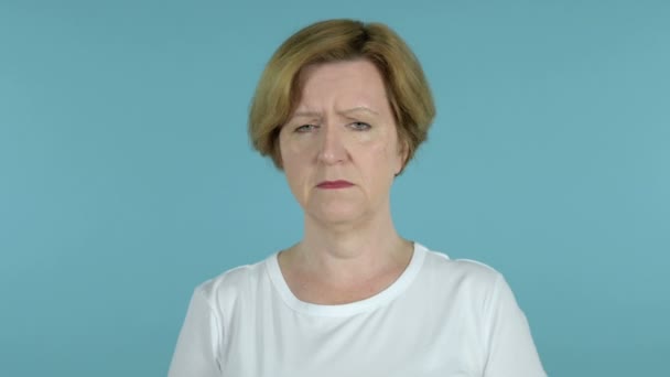 Smutná stará žena izolovaná na modrém pozadí — Stock video