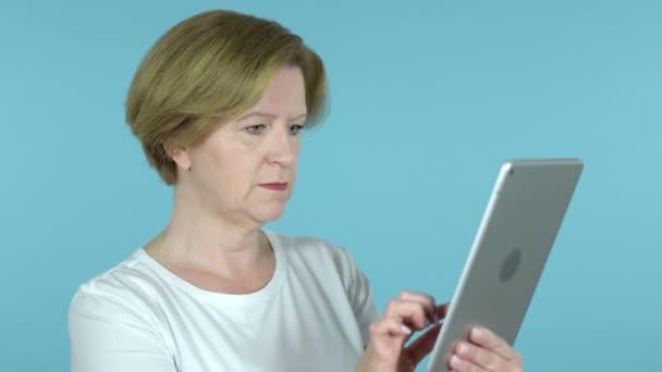 Oude vrouw reageren op verlies op Tablet geïsoleerd op blauwe achtergrond — Stockvideo