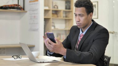 Bilgi için telefon ve laptop kullanarak genç Afrikalı Işadamı