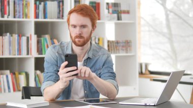 Akıllı telefonda Internet kullanarak genç Casual Redhead adam