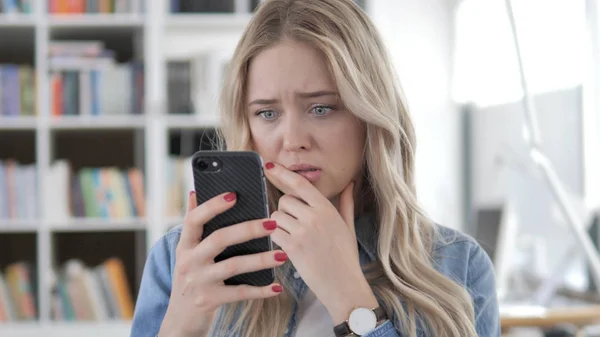 Mujer rubia joven reaccionando a la pérdida en el teléfono inteligente — Foto de Stock