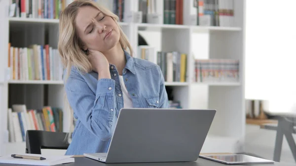 Stanco giovane donna bionda con dolore al collo che lavora sul computer portatile — Foto Stock