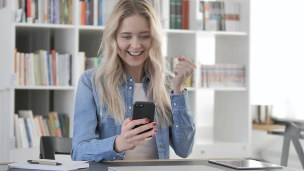 Mujer rubia joven emocionada por el éxito mientras usa el teléfono inteligente — Foto de Stock