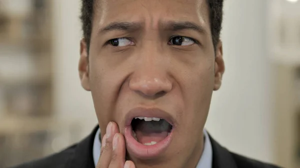 Зубная боль, молодой африканский человек с инфекцией зубов — стоковое фото