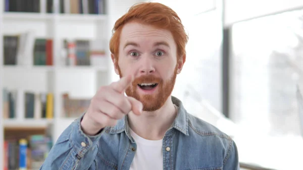 Invitando a un joven hombre pelirrojo casual apuntando hacia la cámara — Foto de Stock