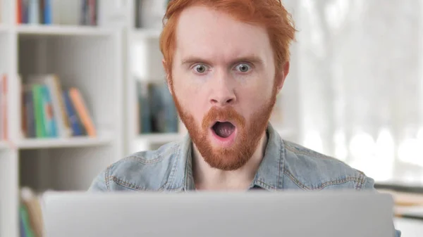 Shocked joven casual pelirroja hombre trabajando en el ordenador portátil — Foto de Stock
