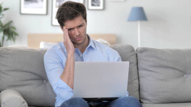 Kanepede otururken baş ağrısı laptop üzerinde çalışan yakışıklı genç adam