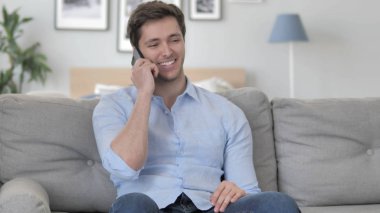 Kanepede rahatlatıcı iken telefonda konuşan genç adam