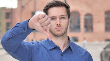 Genç adam ayakta açık thumbs Down