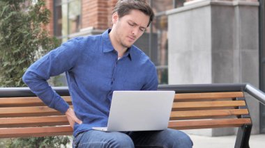 Arka ağrı laptop üzerinde çalışan açık genç adam oturan