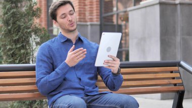 Tablette görüntülü sohbet sırasında konuşan genç adam