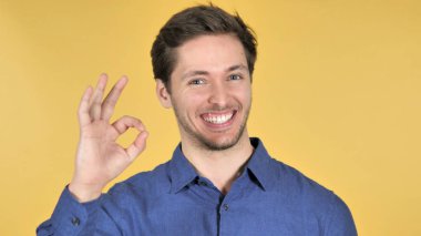 Sarı arka planda Casual genç adam tarafından Tamam jest