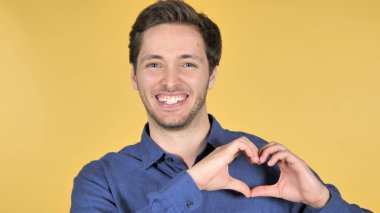 Sarı arka planda Izole genç adam tarafından el yapımı kalp