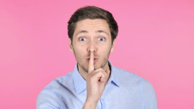 Pembe arka planda Izole genç adam tarafından dudaklar üzerinde parmak
