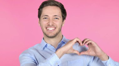 Pembe arka planda Izole genç adam tarafından el yapımı kalp