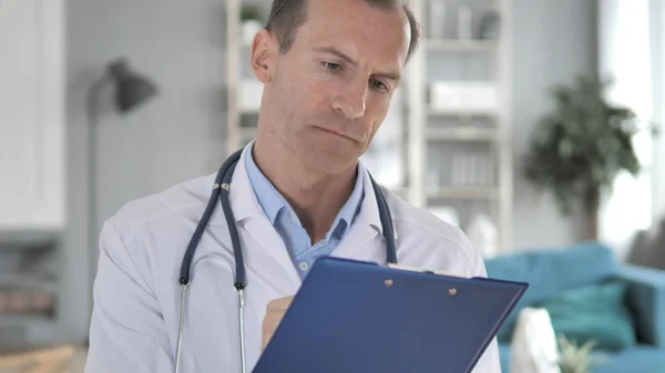 Senior Doctor Reading Medical Report, Doing Paperwork