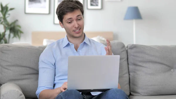 Chat vidéo en ligne sur ordinateur portable par beau jeune homme assis au lieu de travail créatif — Photo