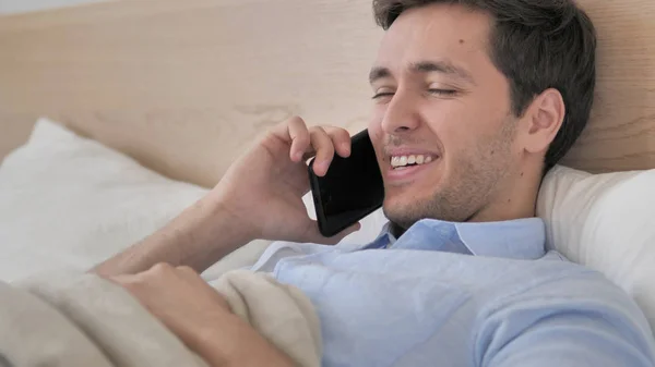 Relaxante jovem falando no telefone na cama — Fotografia de Stock