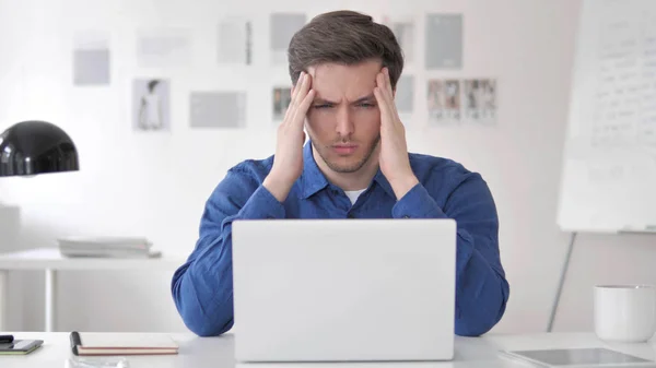 Casual ung man med huvudvärk på jobbet — Stockfoto