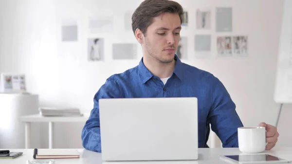 Hombre adulto casual bebiendo café mientras trabaja en el ordenador portátil — Foto de Stock