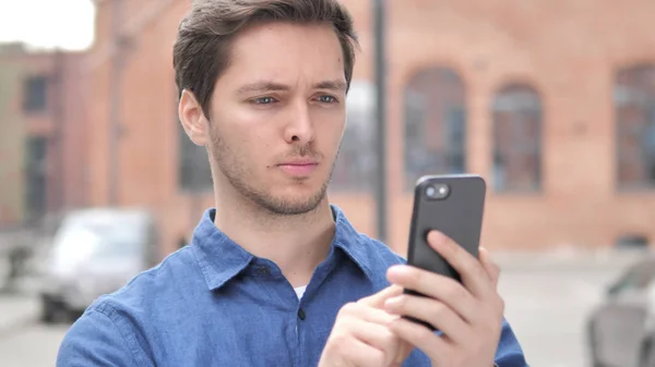 Portrait extérieur de jeune homme utilisant un téléphone intelligent — Photo