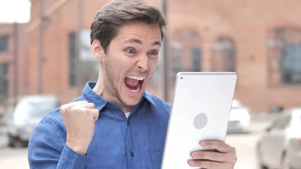 Retrato al aire libre del hombre animando por el éxito en la tableta — Foto de Stock