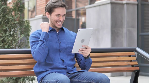 Happy Man Cheering for Success on Tablet, Sitting on Bench — Stock Photo, Image