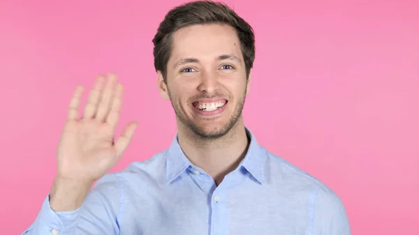Ung man vinka hand att välkomna på rosa bakgrund — Stockfoto