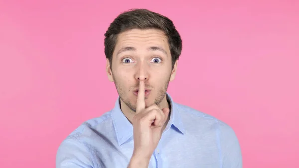 Finger på läppar av ung man isolerad på rosa bakgrund — Stockfoto