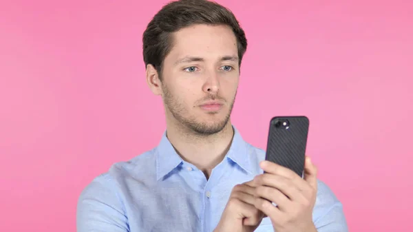 Hombre joven usando Smartphone sobre fondo rosa — Foto de Stock