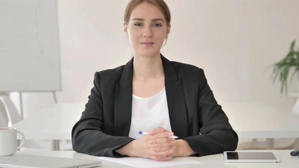 Lächelnde junge Geschäftsfrau im Büro blickt in die Kamera — Stockfoto