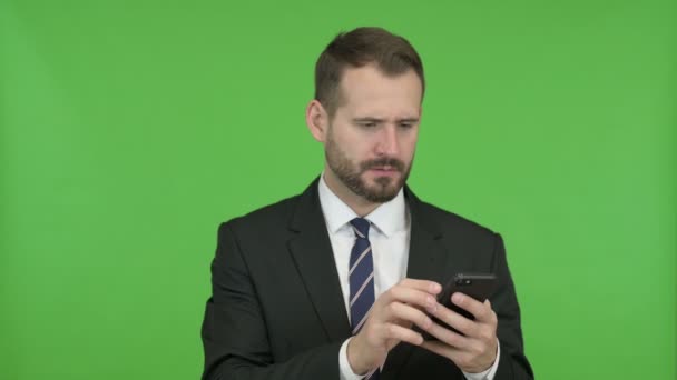 Бизнесмен разочаровывается, когда использует телефон против Chroma Key — стоковое видео