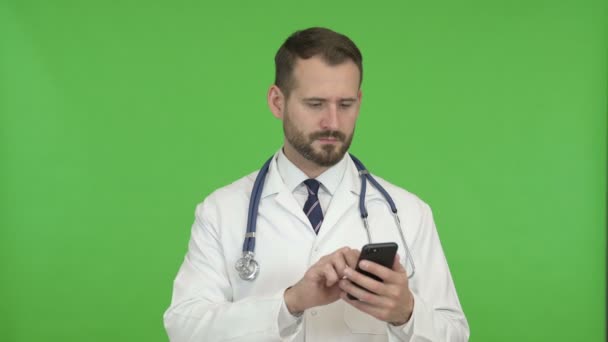 Médico jovem usando telefone celular contra Chroma Key — Vídeo de Stock