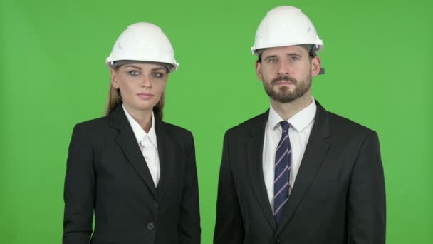 Zwei Bauingenieure lächeln, während sie gegen den Chromaschlüssel in die Kamera schauen — Stockvideo