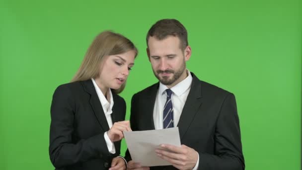 Profissional masculino e feminino estudando documentos contra Chroma Key — Vídeo de Stock