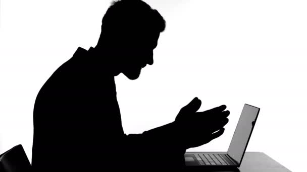 Silhueta do homem perturbado trabalhando em seu laptop — Vídeo de Stock