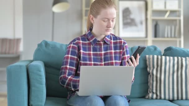 Jonge vrouw met behulp van de telefoon en laptop — Stockvideo